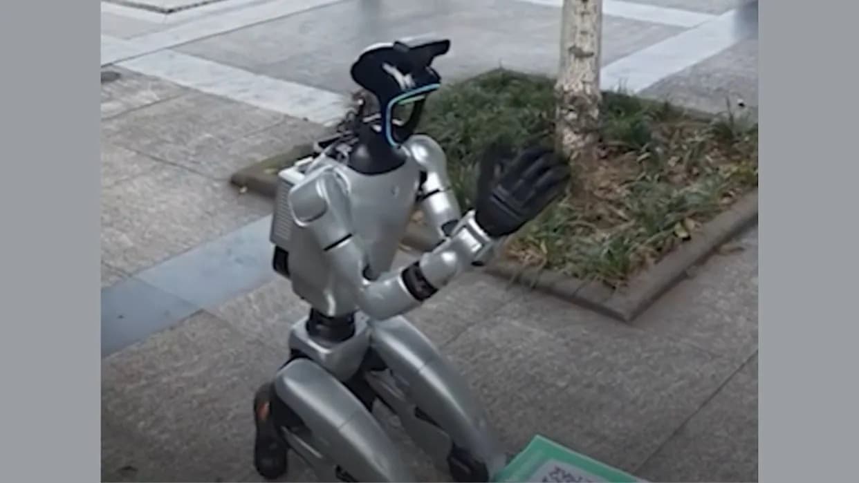 Humanoidni Robot Kleči Na Ulici Sa QR Kodom — Unitree G1 'Moli' Za Punjenje Baterije
